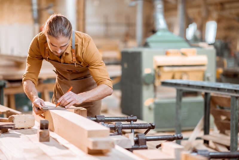 Carpenter marking a board with a speed square